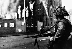 Riots in Belfast British Troops stand Guard in Falls Road Belfast Soldier standing with a gun looking at a burning building. B3P332